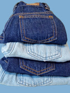 Stack of folded blue jeans on a light background, Denim fabric detail of Grow-Ease™ kids jeans highlighting durable construction for repeated wear